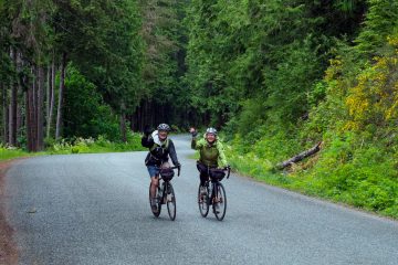 Two happy cyclists biking on British Columbia's "Spirit Loop", following the finest coastal roads and an optional portion of the Cowichan Valley Trail.