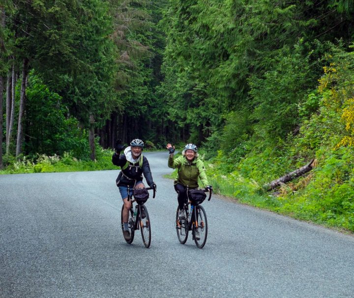 Two happy cyclists biking on British Columbia's "Spirit Loop", following the finest coastal roads and an optional portion of the Cowichan Valley Trail.