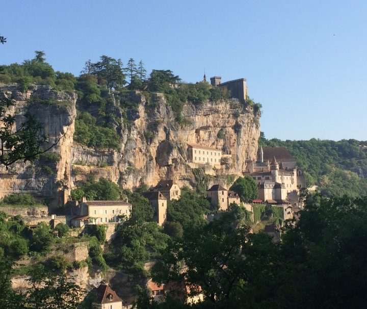 A cliff with buildings neatly nestled into the cliff face, blending with the landscape in Rocamadour on the Dordogne Valley Bike or Walking Tour with Freewheeling Adventures.