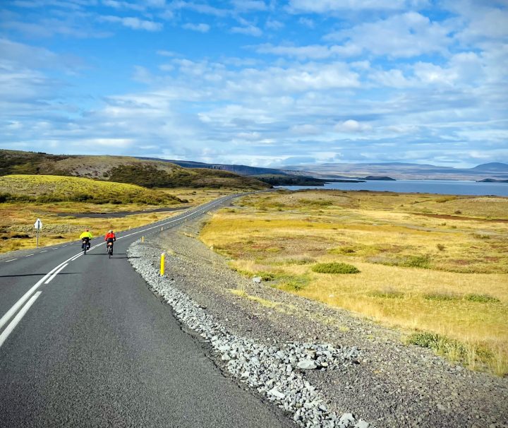 2 cyclists riding along a deserted coastal road were the scenery is always superb and unobstructed by forests in south Iceland with Freewheeling Adventures.