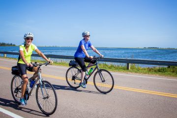 2 happy cyclists riding along one of Prince Edward Islands many stretches of low traffic coastal roads off the beaten path of the Confederation Trail.