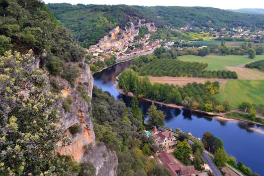 A cliff with buildings neatly nestled into the cliff face, blending with the landscape near Rocamadour on the Dordogne Valley Bike or Walking Tour with Freewheeling Adventures.