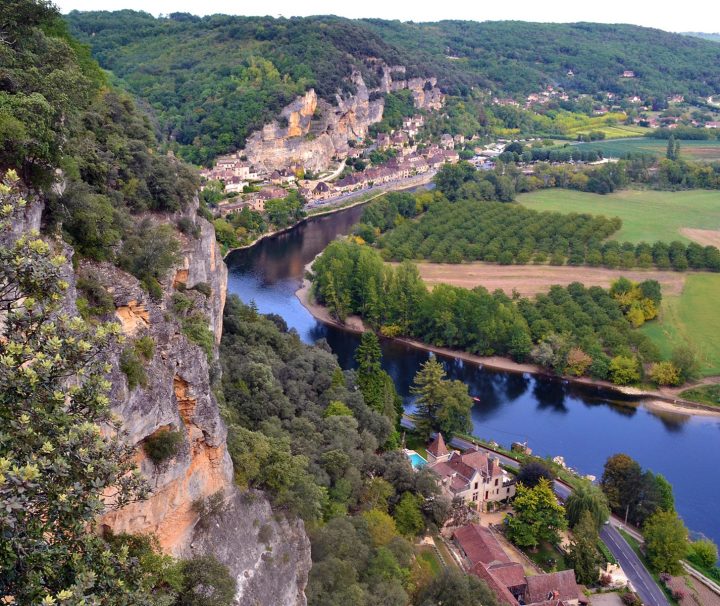 A cliff with buildings neatly nestled into the cliff face, blending with the landscape near Rocamadour on the Dordogne & Lot Bike.