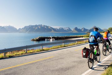 Cyclist riding away on a flat seaside road on tour with Freewheeling.