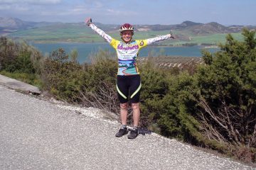 A cyclist full of joy with a mountain backdrop on a beautiful day on the challenging Spain: Andalucía Bike Tour with Freewheeling Adventures.