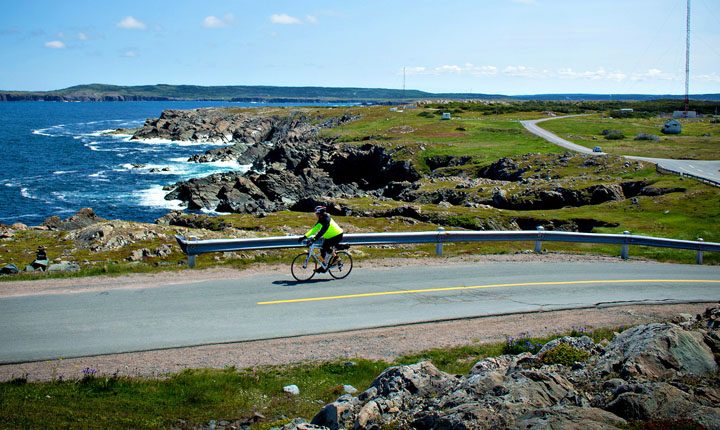 A cyclist touring along the scenic, rugged coastline of Atlantic Canada, near the East Coast of Newfoundland.