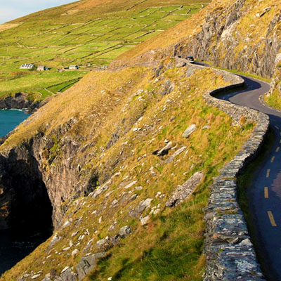 This image depicts a scenic coastal drive along the Dingle Peninsula in County Kerry, Ireland