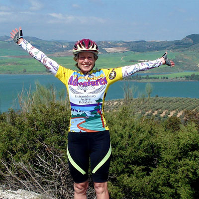 This image depicts a cyclist celebrating at a viewpoint during a scenic Andalusian bike tour in southern Spain