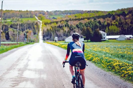 This image shows a person cycling on the quiet gravel roads of the Eastern Townships of Quebec