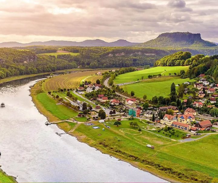 The image shows a scenic view of the Elbe River meandering through the Saxon Switzerland National Park in Germany