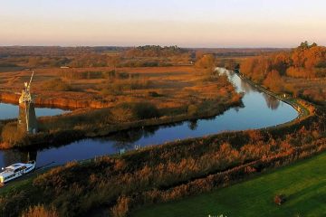 This image depicts a serene moment in The Broads National Park, a vast network of navigable waterways and wetlands in England