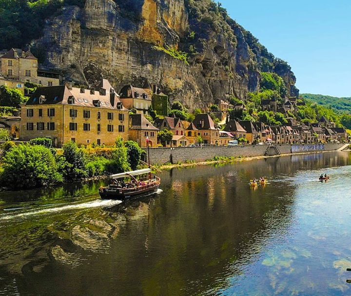 This image shows the scenic village of La Roque-Gageac situated along the Dordogne River in southwestern France