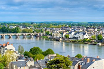 This image depicts a scenic view of the Loire River flowing through the town of Saumur in the Loire Valley region of France