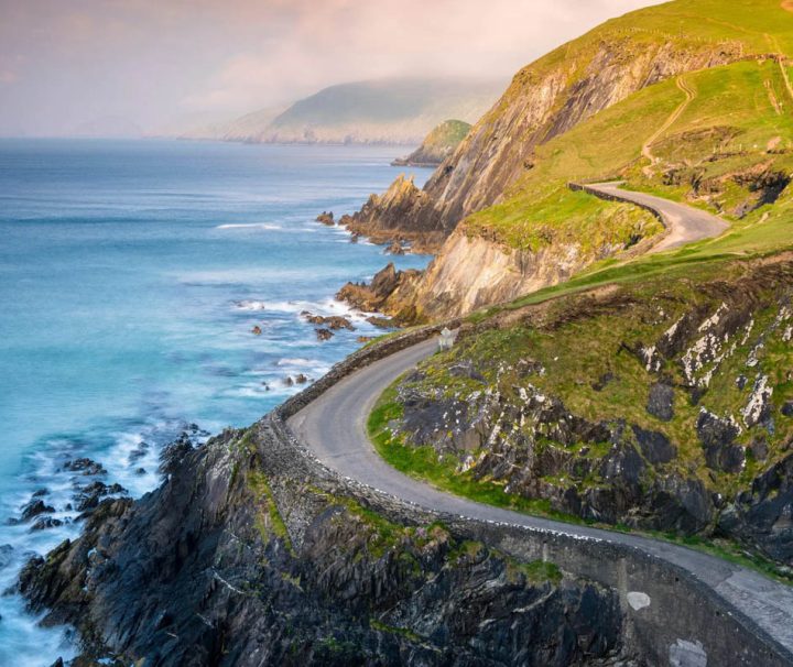 This image depicts a scenic coastal drive along the Dingle Peninsula in County Kerry, Ireland