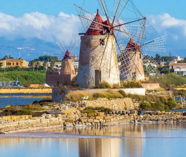 This image shows the historic windmills at the Saline dello Stagnone (Stagnone Salt Pans) near Marsala, Sicily