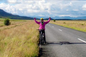 This image captures a cyclist pausing for a photo on a scenic road in Southern Iceland