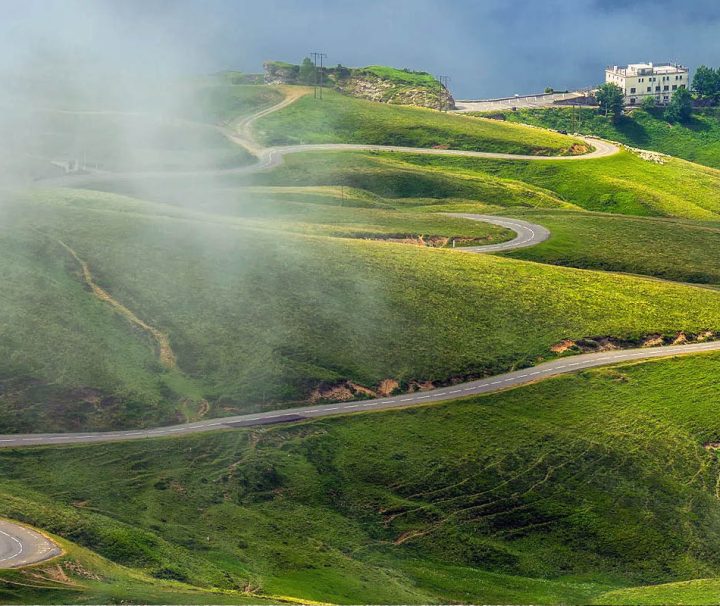 A scenic, winding mountain road known as a hairpin turn or switchback route, often found in hilly landscapes in the Pyrenees foothills